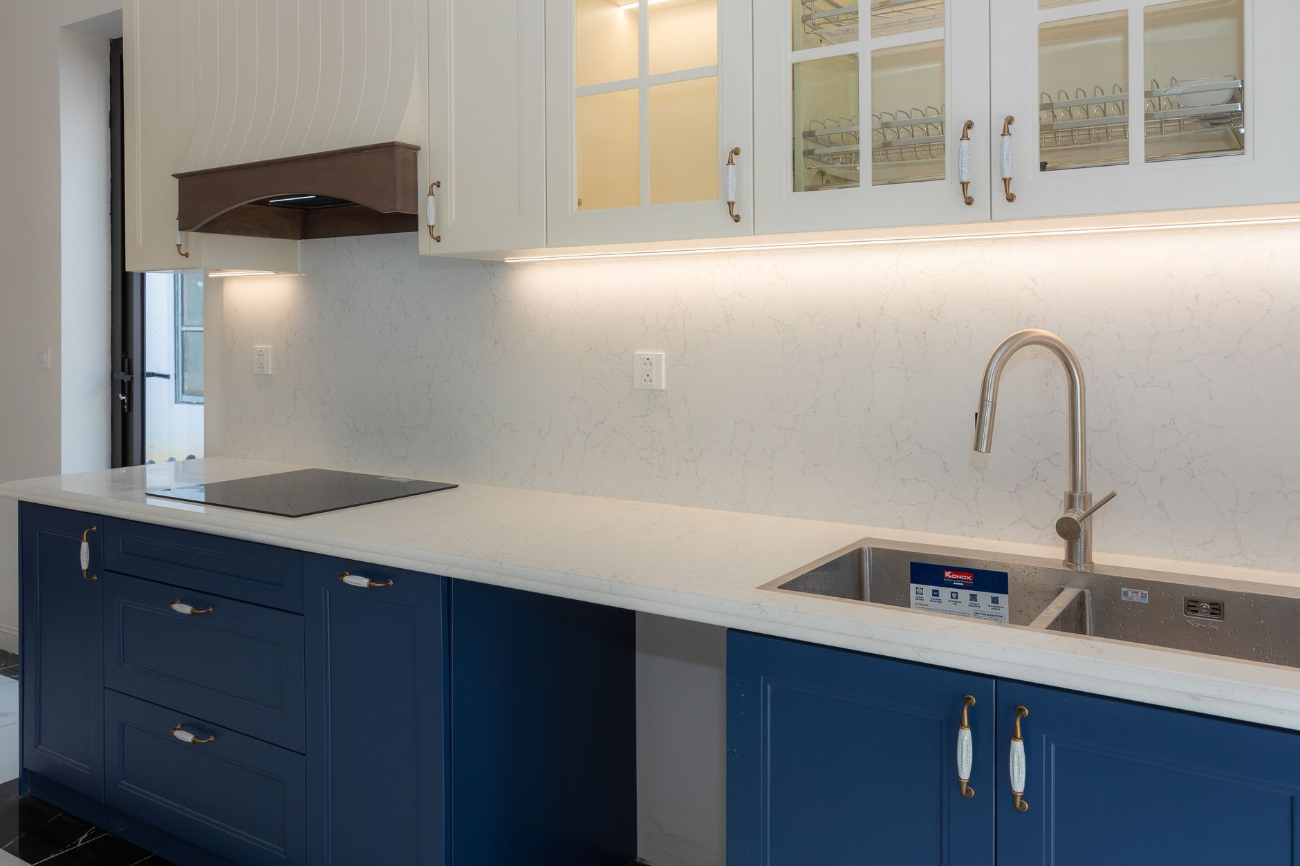 Nieuw gerenoveerde keuken met blauwe onderkasten, witte bovenkasten en marmeren werkblad
